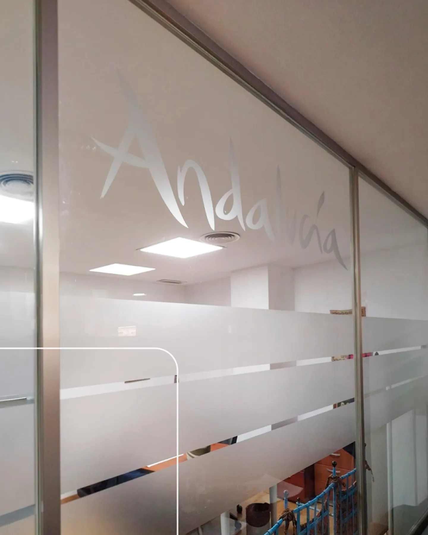 Vinilo al ácido con efecto glaseado y la marca Andalucía en cristalera interior de la oficina