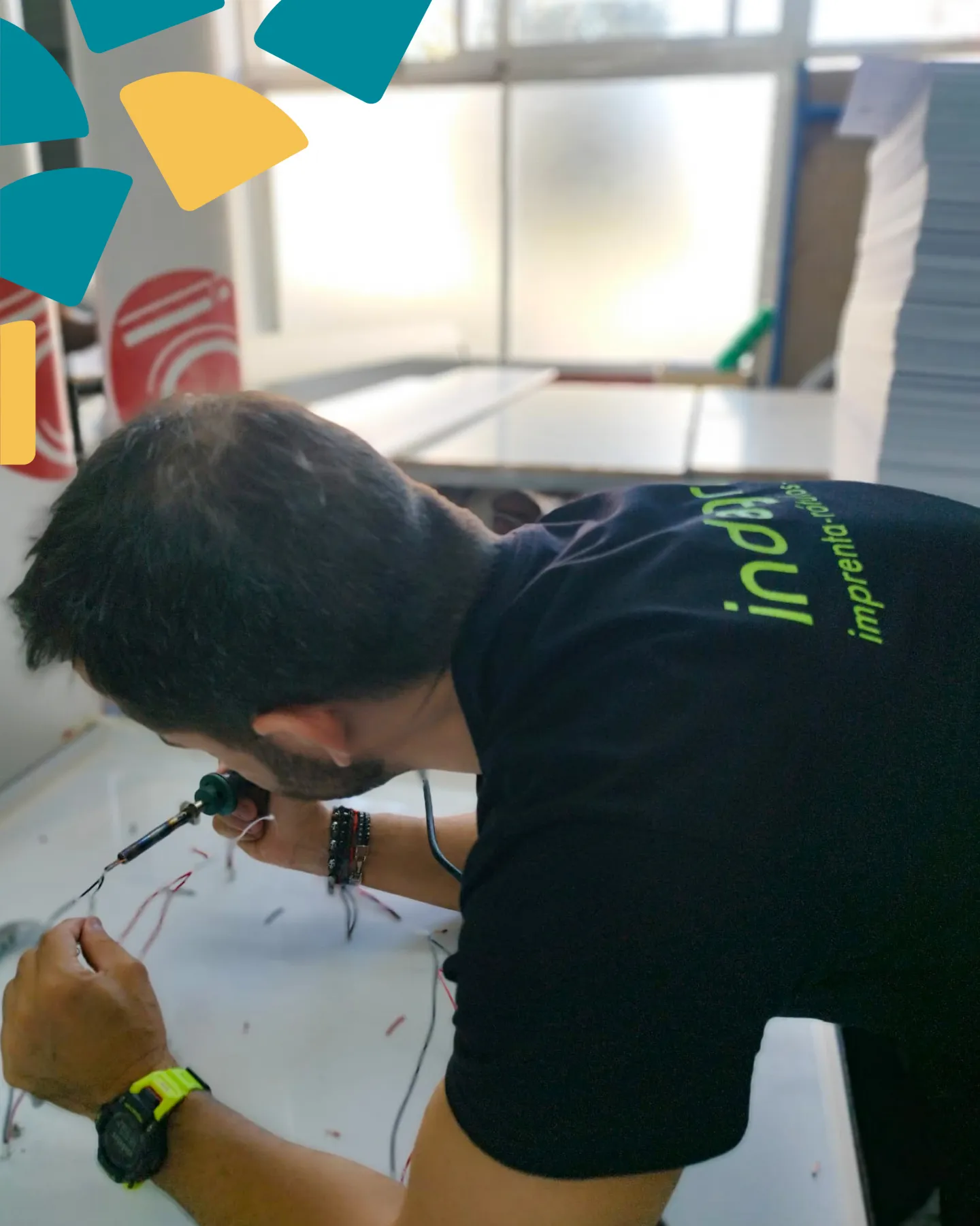 Técnico de Indagrafic soldando cables durante la fabricación de rótulos luminosos en el taller de Málaga