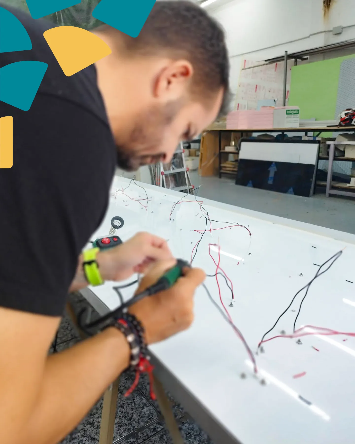 Técnico de Indagrafic soldando cables sobre un panel durante la fabricación de rótulos luminosos