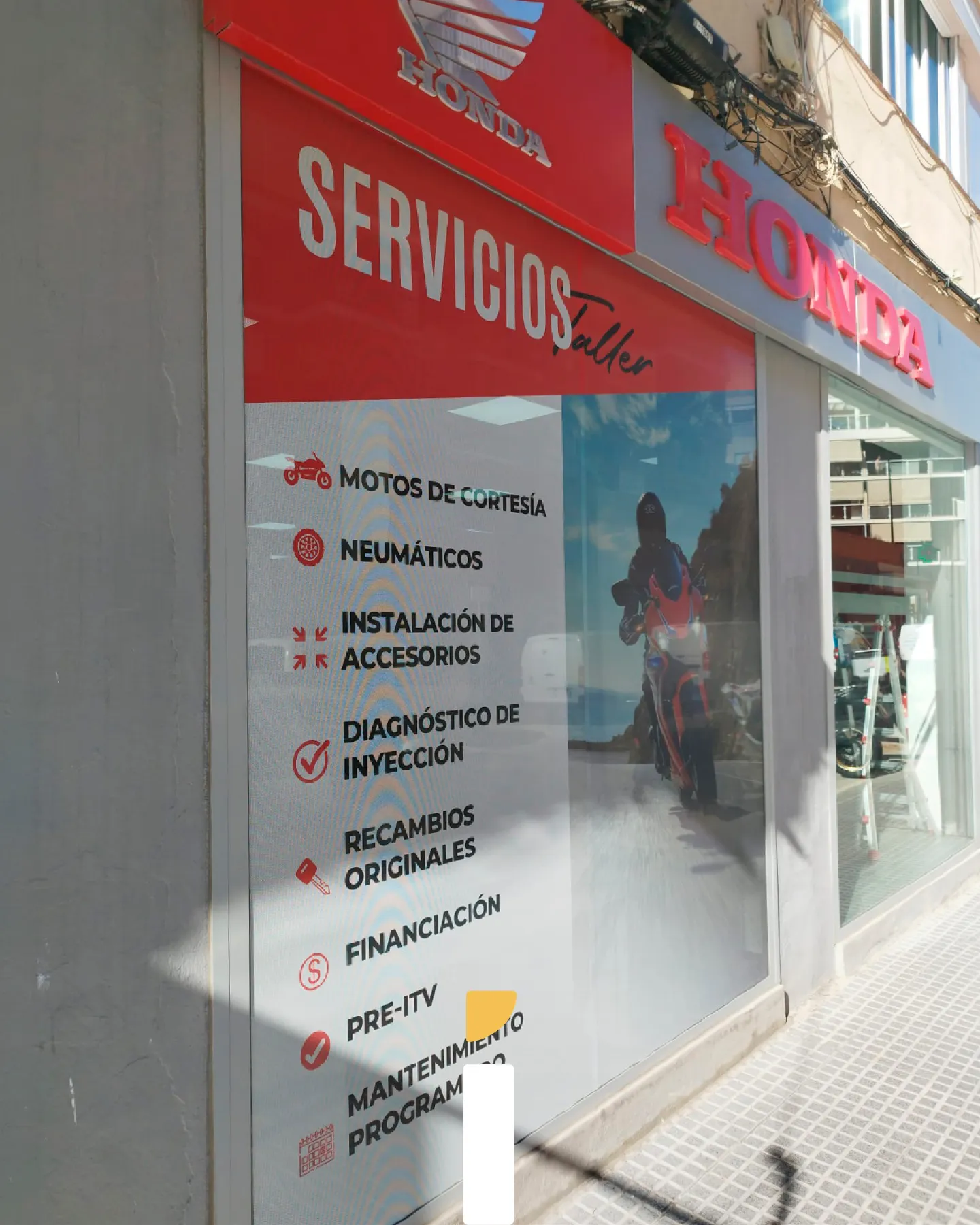 Rotulación del concesionario Honda en la cristalera con vinilo microperforado y la lista de servicios de taller