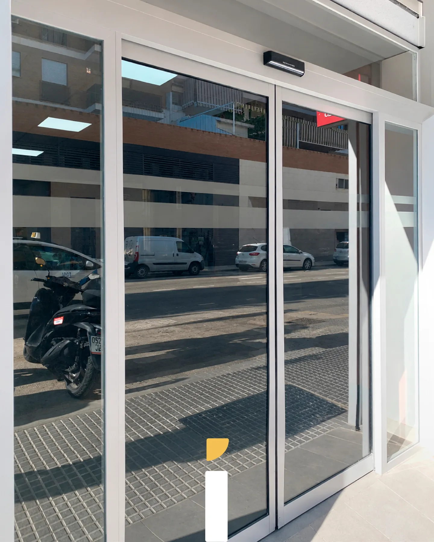 Puertas acristaladas de acceso al concesionario Honda con vistas despejadas hacia la calle