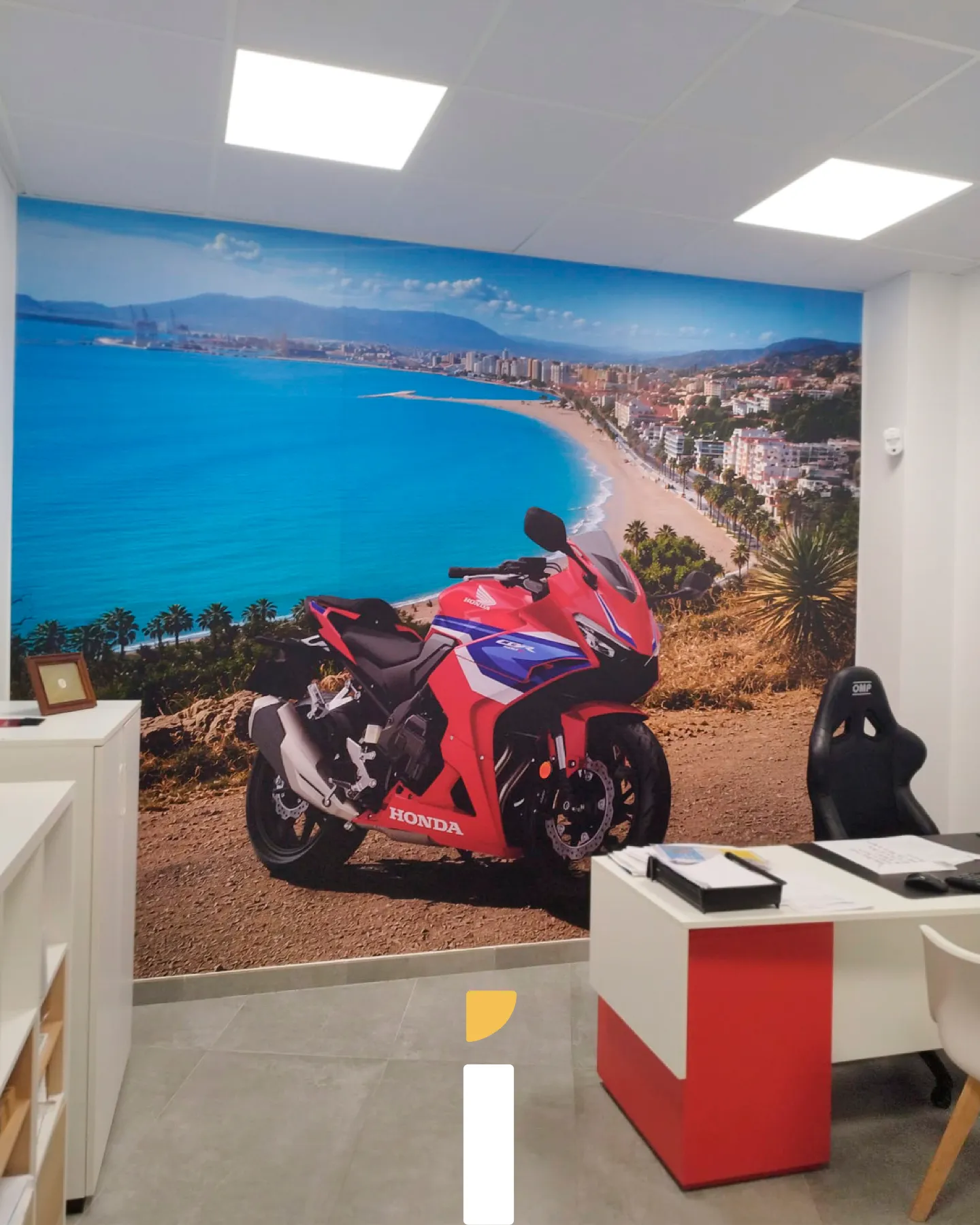 Rotulación del concesionario Honda en la pared interior con un mural de una Honda CBR roja frente a una bahía